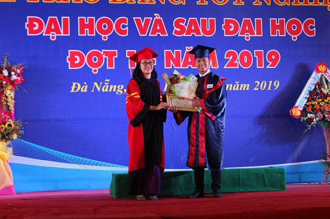 A person standing on a stage in front of a signDescription automatically generated