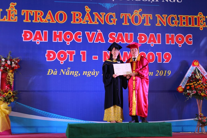 A person standing on a stage in front of a signDescription automatically generated