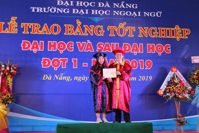 A person standing on a stage in front of a signDescription automatically generated