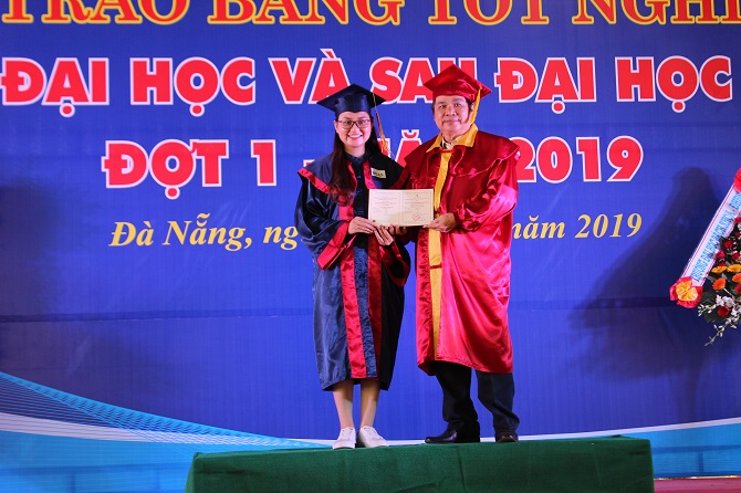 A person standing on a stage in front of a signDescription automatically generated