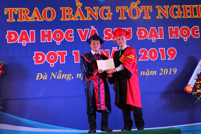 A person standing on a stage in front of a signDescription automatically generated