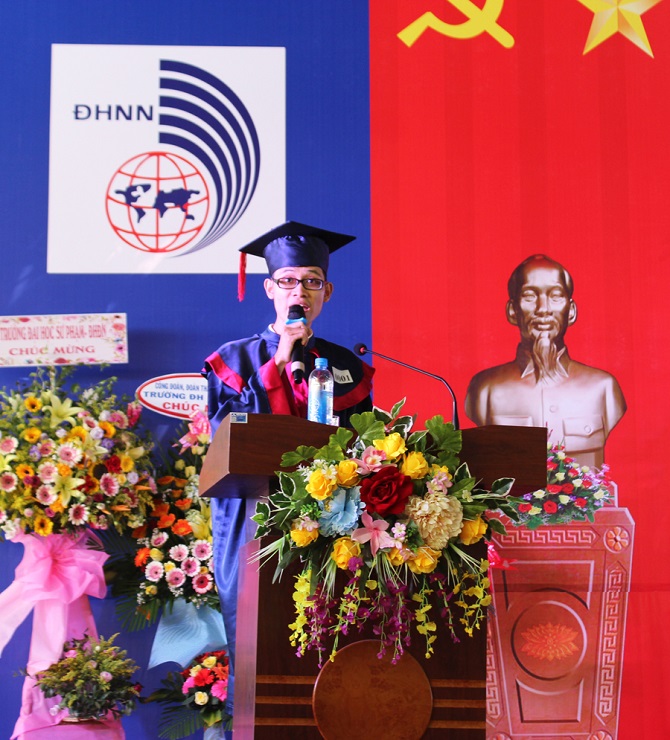 A person standing in front of a red flowerDescription automatically generated