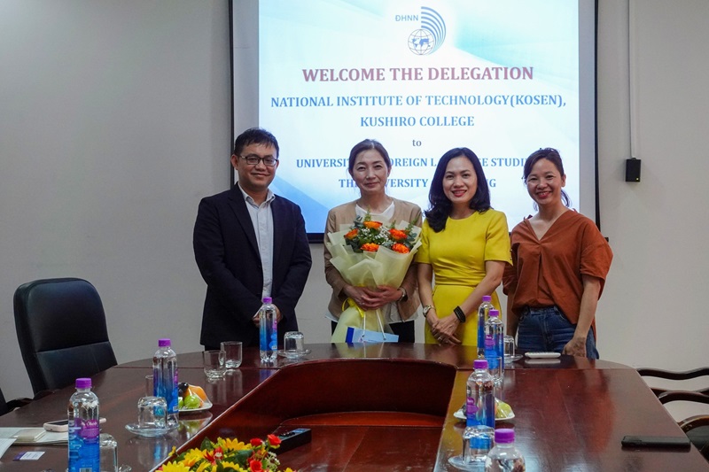 A group of people standing in front of a table with a large screenDescription automatically generated